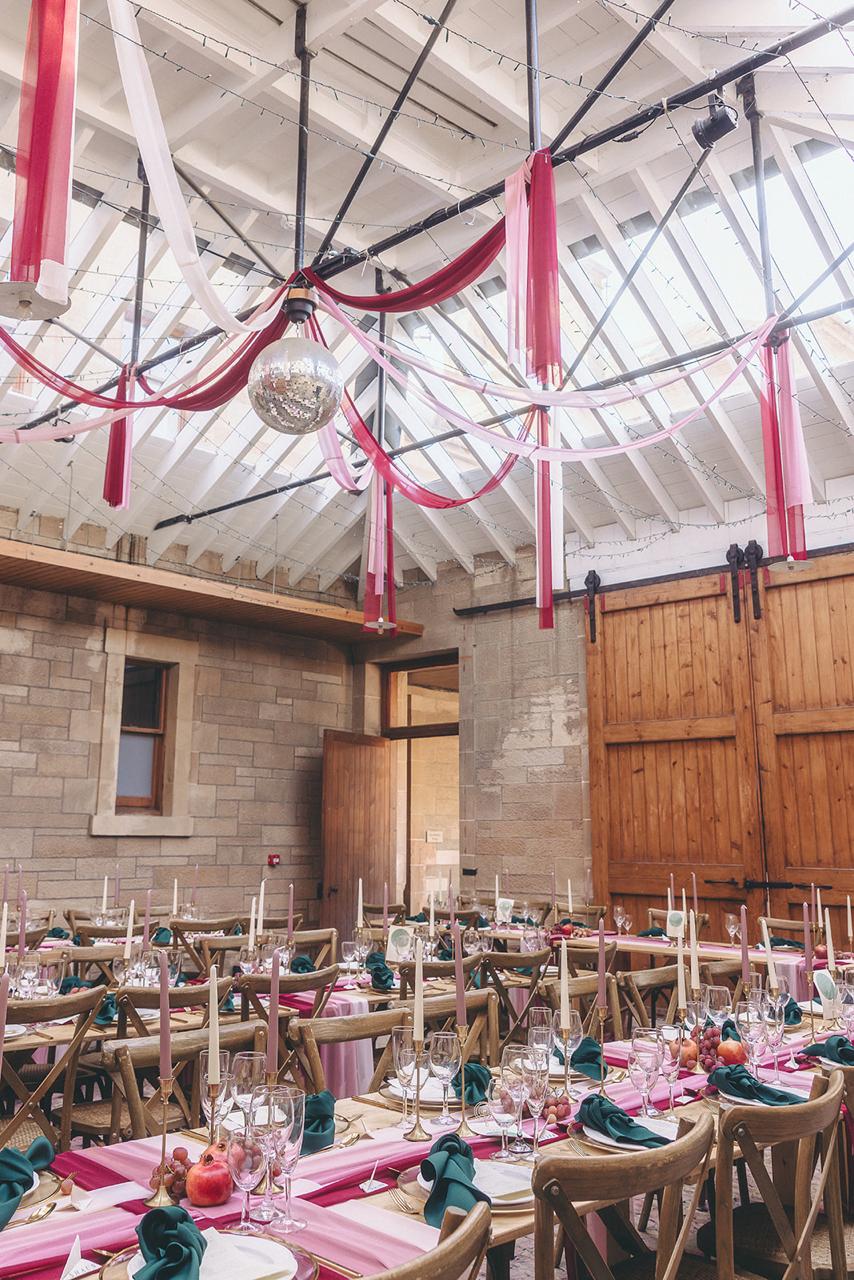 Barn wedding reception with draped ceiling and crossback chairs