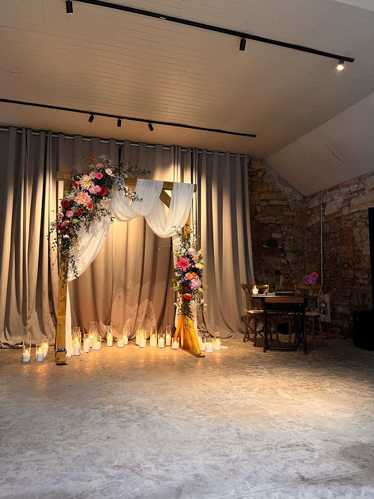 Ceremony arch with floral arrangements and candlelit aisle